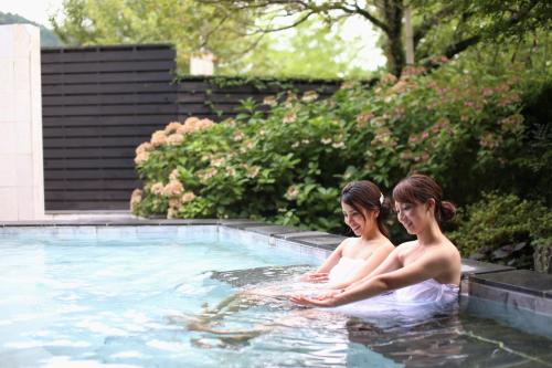two people are sitting in a swimming pool at Okutsu Onsen Komeya Club in Kagamino