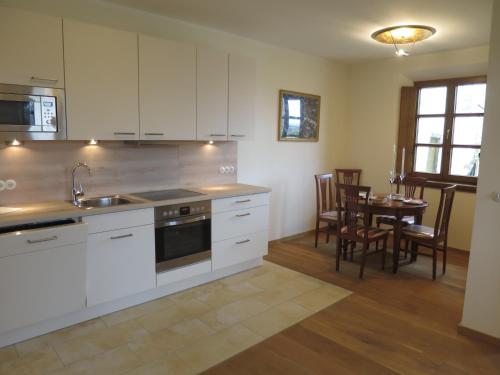 a kitchen with white cabinets and a table with chairs at Ferienwohnung am Blasturm in Schwandorf in Bayern