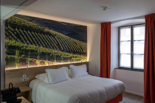a bedroom with a bed with a large painting on the wall at Hotel KLE, BW Signature Collection in Kaysersberg