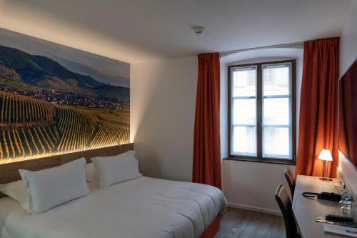 a bedroom with a bed and a desk and a window at Hotel KLE, BW Signature Collection in Kaysersberg