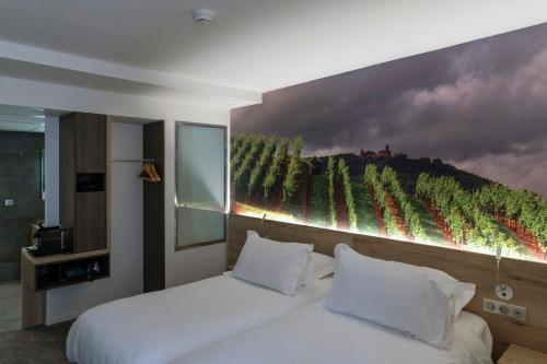 a bedroom with a bed with a painting on the wall at Hotel KLE, BW Signature Collection in Kaysersberg