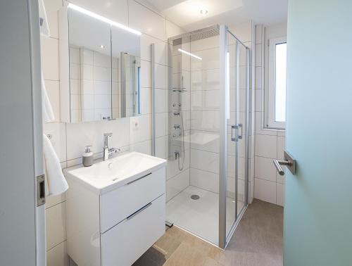 ein weißes Bad mit einem Waschbecken und einer Dusche in der Unterkunft Premium Business Apartment in Oberkochen in Oberkochen