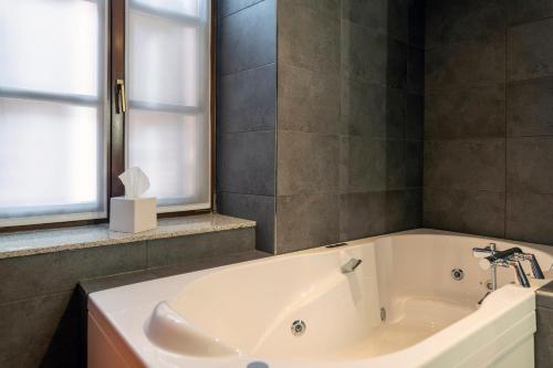 a white bath tub in a bathroom with a window at Hotel KLE, BW Signature Collection in Kaysersberg