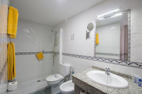 La salle de bains blanche est pourvue d'un lavabo et de toilettes. dans l'établissement Hotel Green Field, à Playa del Ingles