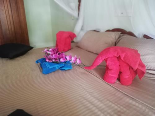 a pink stuffed elephant on a bed with flowers at Mahi Villa in Bentota