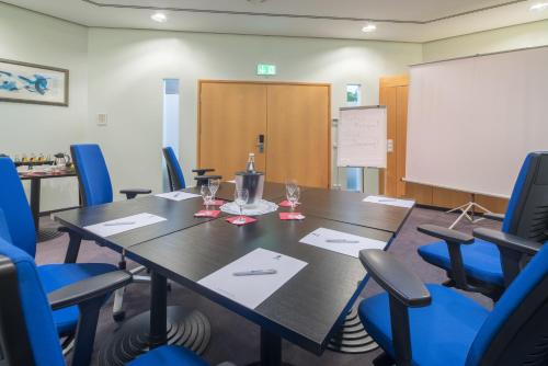 a conference room with a table and chairs and a whiteboard at Best Western Hotel im Forum Mülheim in Mülheim an der Ruhr