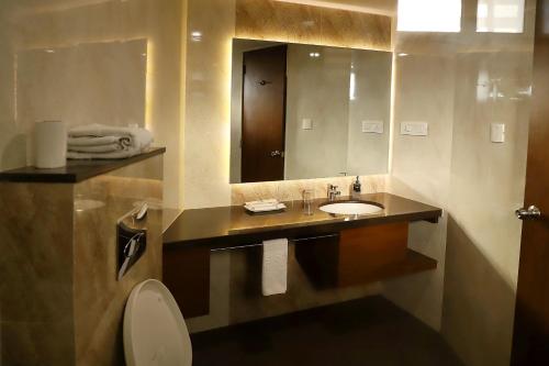 a bathroom with a sink and a mirror at Patria Suites in Rajkot