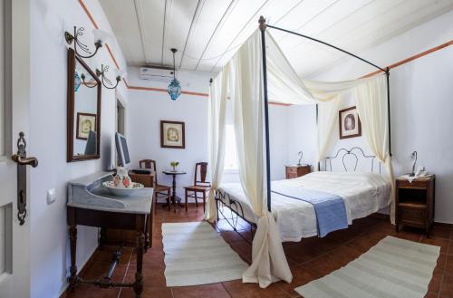 a bedroom with a canopy bed and a desk at Nostos Guesthouse in Kythira