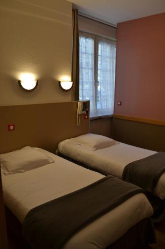 two beds in a room with two lights on the wall at Hôtel La Porte Saint Pierre-Logis Hôtel Intra Muros in Saint Malo