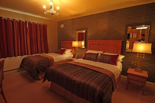 a hotel room with two beds and a chandelier at Errigal Country House Hotel in Cootehill
