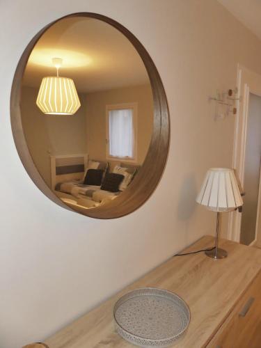 a mirror on a wall with a couch and a lamp at Les Ambaciales in Amboise