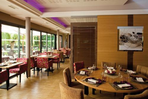 a dining room with tables and chairs in a restaurant at Kyriad Nantes Sud - Bouaye Aéroport in Bouaye