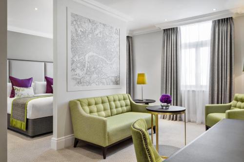 a hotel room with a bed and a couch and chairs at St. James' Court, A Taj Hotel, London in London