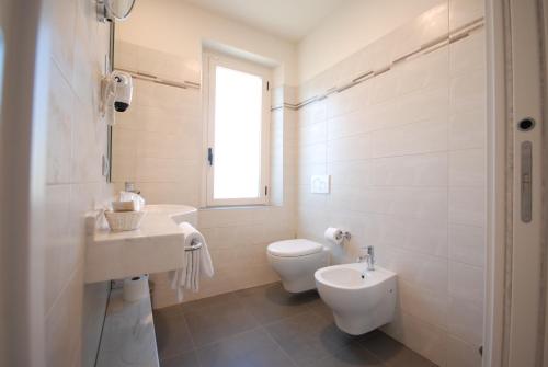 a white bathroom with a toilet and a sink at Hotel Giardino in Bibbiena