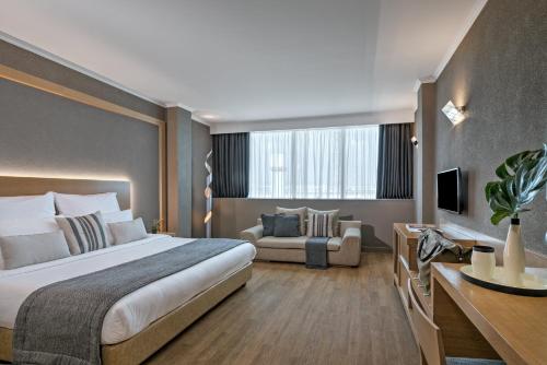 Porto Palace Hotel Thessaloniki في سلانيك: غرفة فندقية بسرير كبير واريكة