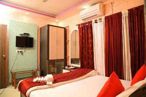a hotel room with two beds and a television at Babul Hotel in Kolkata