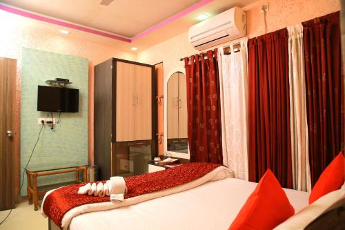 a hotel room with two beds and a television at Babul Hotel in Kolkata