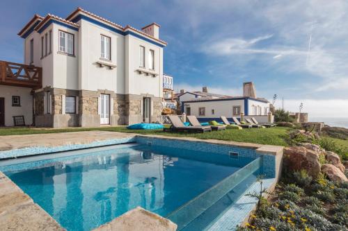 une villa avec une piscine en face d'une maison dans l'établissement Chalet O Amorzinho Sintra Praia, à Sintra