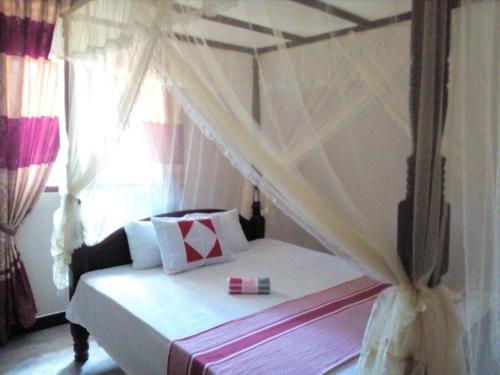a bedroom with a canopy bed with a window at Sajini Villa in Weligama