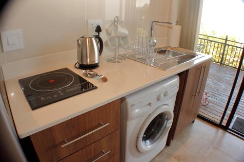 a kitchen with a stove and a washing machine at Keret Accommodation in Bellville