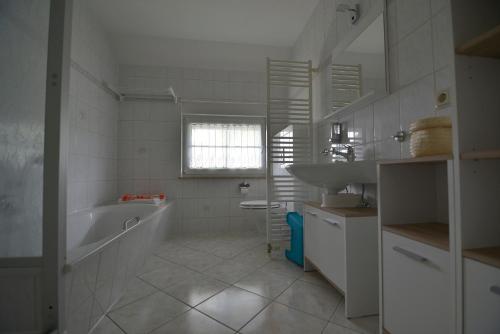 a white bathroom with a tub and a sink at Ferienwohnung am großen Stein in Leutersdorf
