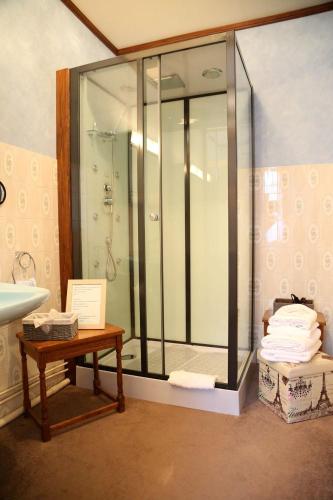 La salle de bains est pourvue d'une douche, d'une table et d'un lavabo. dans l'établissement Le Robinson, à Mézières-sur-Oise