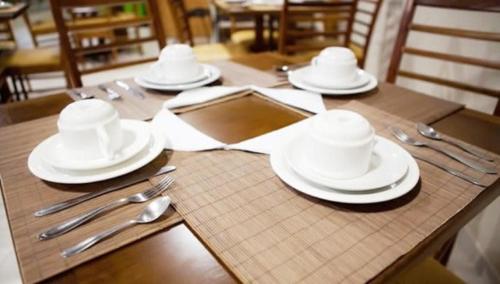 a wooden table with white plates and silverware on it at Flex Hotel in Canoinhas