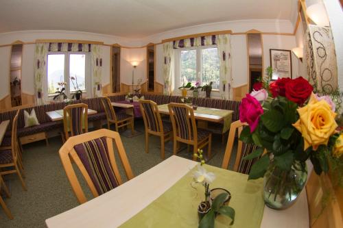 a restaurant with tables and chairs and flowers in a vase at Kamenhof in Weissensee