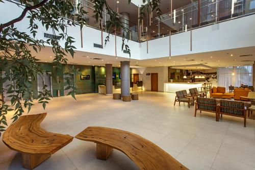 a lobby with wooden benches in a building at Mercure Salvador Rio Vermelho in Salvador