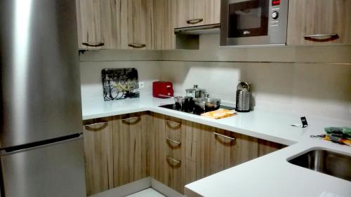 エル・プエルト・デ・サンタマリアにあるApartamento Santa Fazのキッチン(木製キャビネット、ステンレス製の冷蔵庫付)