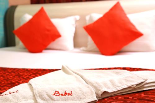 a bed with red and white pillows and a towel at Babul Hotel in Kolkata