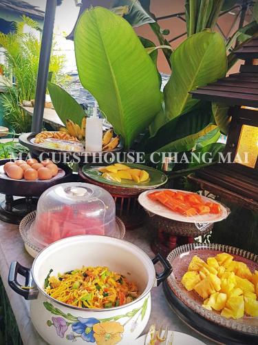 a table with plates of food and bowls of food at Ma Guesthouse Chiang Mai in Chiang Mai