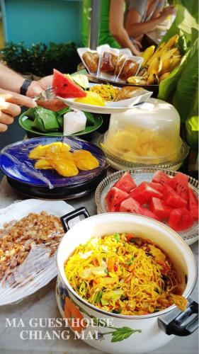 a table topped with plates of food and bowls of food at Ma Guesthouse Chiang Mai in Chiang Mai