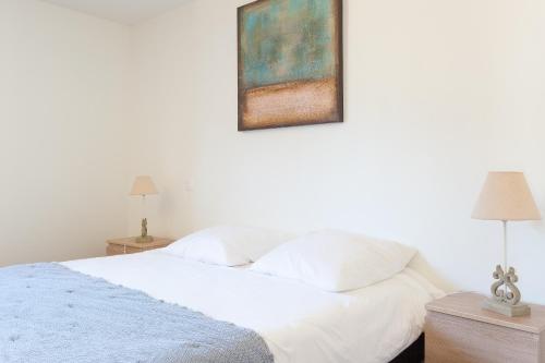 a bedroom with a white bed with a painting on the wall at Bellevues-Sur-Mer, à 100 m de la plage in Trévou-Tréguignec