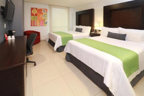 a hotel room with two beds and a television at Wyndham Garden Guadalajara Acueducto in Guadalajara