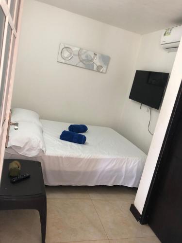 a small bedroom with a white bed and a television at Apartamentos Martinez in San Andrés