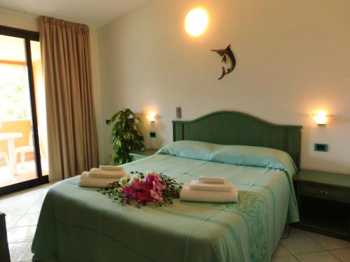 ein Schlafzimmer mit einem grünen Bett und Handtüchern darauf in der Unterkunft Hotel Blu Marlin in Villasimius