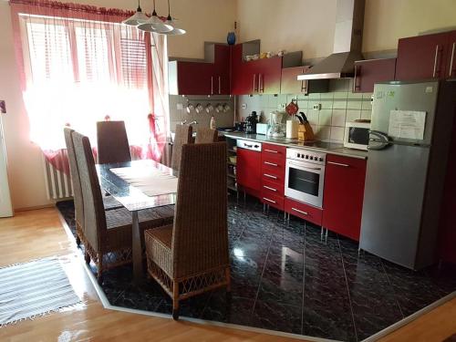 a kitchen with red cabinets and a table and a refrigerator at Szőke Tisza Vendégház in Szajol