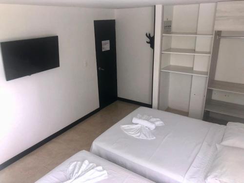 a room with two beds and a tv and shelves at Apartamentos Martinez in San Andrés