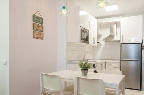 a white kitchen with a white table and chairs at Apartamento El Parque con Vistas al Mar in Almería
