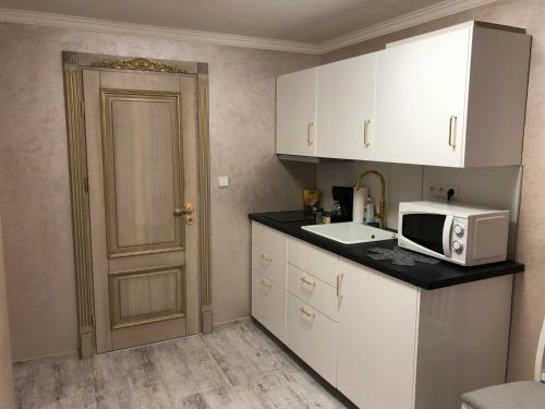 cocina con armarios blancos, microondas y puerta en Ioannis, en Karlovy Vary