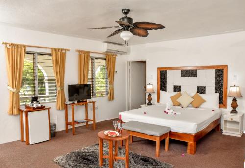 a bedroom with a large white bed and a tv at Beyond Sunset Resort & Villas in Treasure Beach
