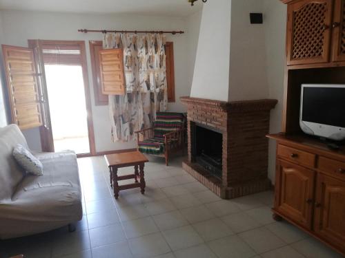 a living room with a fireplace and a tv at Apartamentos Cerro Negro in Capileira