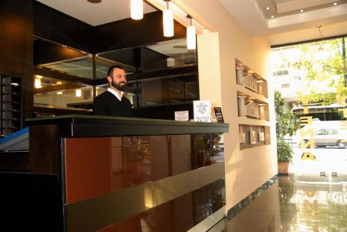 a man in a suit standing at a counter at Vienna Hotel in Athens