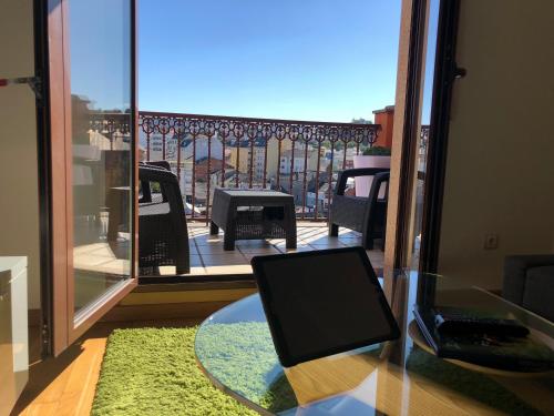 een glazen tafel met een laptop op het balkon bij High Rentxacobeo in Sarria