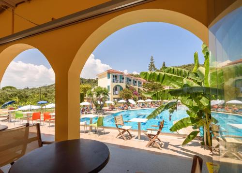 a patio area with a pool, chairs, and tables at Sunrise Zante - Adults Only Hotel in Tsilivi