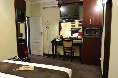 a hotel room with a bed and a desk with a microwave at City Stay in Maseru