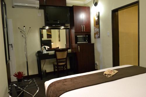 a hotel room with a bed and a desk and a television at City Stay in Maseru