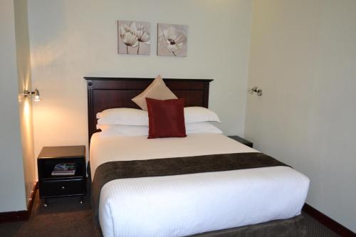 a bedroom with a bed with a red pillow on it at City Stay in Maseru