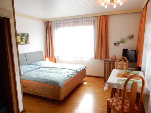 a bedroom with a bed and a table and a window at Ferienwohnung Reichmann in Bodensdorf